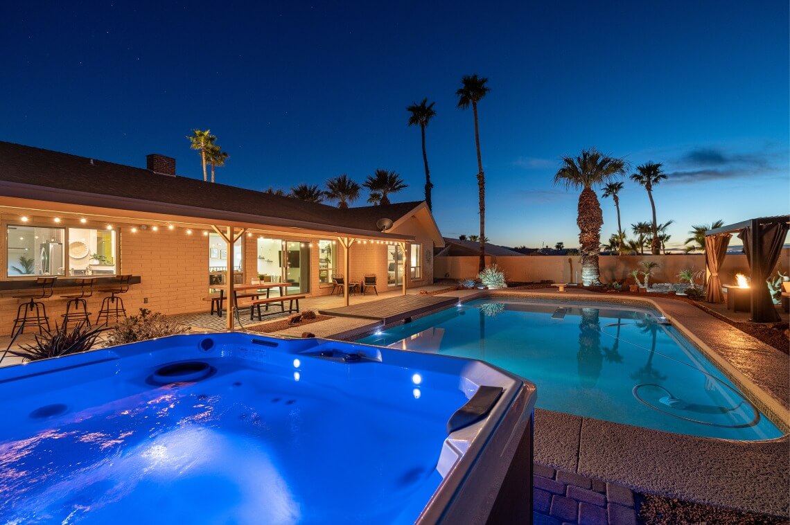 Dusk view of Airbnb backyard with pool and hot tub, perfect for relaxing vacations.
